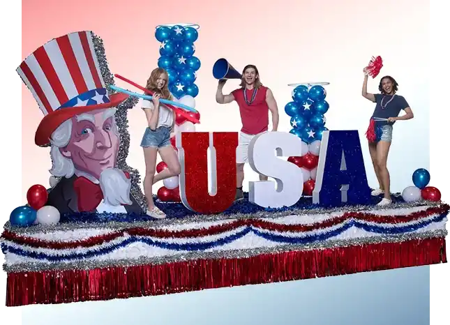Parade float with large USA letters, red white and blue tinsel, balloons, and patriotic decorations styled for a festive celebration.