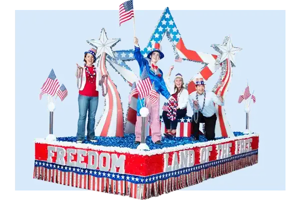 Patriotic parade float with red white and blue stars, American flags, and Freedom Land of the Free lettering with festive fringe.