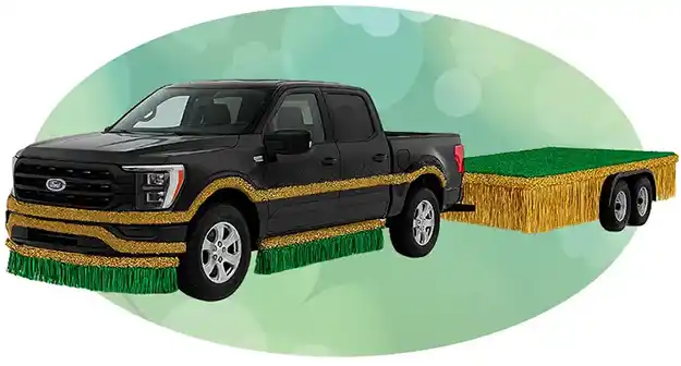 Black pickup truck towing a parade float platform decorated with green and gold fringe.