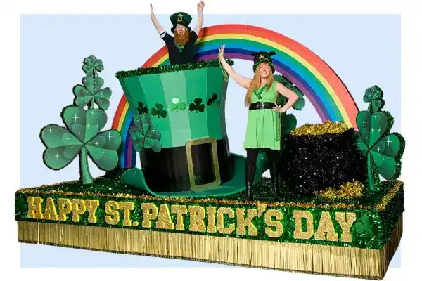 St. Patrick's Day float decorated with large green shamrocks, a giant leprechaun hat, a rainbow backdrop, and gold fringe reading "HAPPY ST. PATRICK'S DAY."